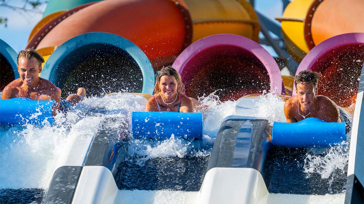 three friends sliding down Kowabunga Racer ride at Big Kahuna's in Destin, Florida, USA